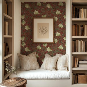 May include: A white bench with two beige pillows and a framed botanical print, set against a red and green floral wallpaper in a built-in alcove with bookshelves.