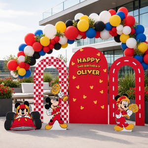 May include: A party decoration set featuring a balloon arch in red, yellow, blue, white, and black. It includes three arched backdrops: one red and white checkered, one solid red with the text Happy 2nd Birthday Oliver, and one red with white road markings. Three Mickey Mouse cutouts are present.