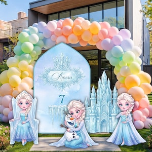 Op de afbeelding: Een feestachtergrondset met een groot boogbord met de naam Aurora en het cijfer 7, geflankeerd door drie karakteruitsparingen en een ijskasteel. Een grote ballonnenboog in pastelkleuren omlijst het geheel op een gazon.