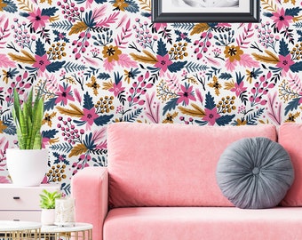 May include: A pink sofa with a gray pillow sits in front of a wall covered in floral wallpaper. The wallpaper features a repeating pattern of pink, blue, and gold flowers and leaves. A black picture frame hangs on the wall above the sofa.