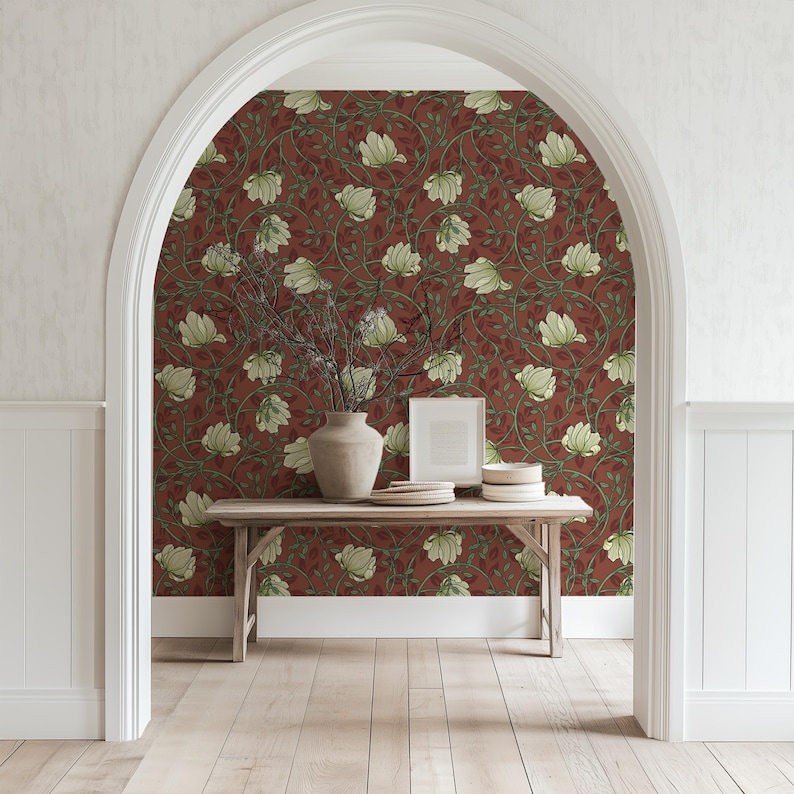 May include: A hallway with white walls and a wooden floor. A wooden table with a vase and books sits in front of a wall covered in red wallpaper with a white floral pattern.