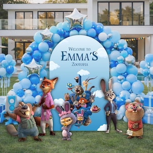 May include: A blue arched backdrop featuring the text Welcome to Emma's Zootopia, surrounded by a large balloon garland in shades of blue and white with silver star-shaped balloons. Several Zootopia character figures stand in front.