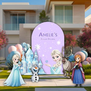 May include: A purple arched backdrop featuring the text Amelie's Frozen Dreams, surrounded by illustrations of Elsa, Anna, Olaf, and a reindeer. A light blue ice castle and clusters of pastel balloons are positioned in front of the display.