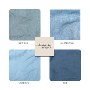 K&ouml;nnte beinhalten: Vier Stoffmuster in den Farben Graublau, Blaumelange, Hellblau und Blau. Ein quadratisches Etikett in der Mitte zeigt den Text "handmade WITH LOVE" mit einem kleinen Herzsymbol. Die Textilien weisen eine sichtbare Webstruktur auf.