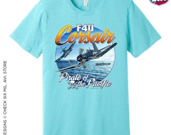May include: A turquoise blue t-shirt with a graphic of a blue and white F4U Corsair airplane flying over the ocean. The graphic includes the text "F4U Corsair" and "Pirate of the Pacific".