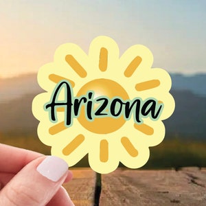 May include: A yellow sun with a stylized sunburst design and the word "Arizona" written in black text on a green background.