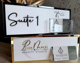 May include: Two rectangular signs with white backgrounds and black or gold frames. The top sign features black text reading Suite 1 and a clear acrylic card holder. The bottom sign displays gold text reading Pearl Moon Beauty Studio and a clear card holder.