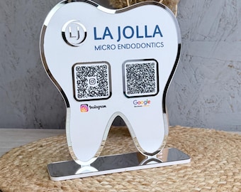 May include: A white, tooth-shaped acrylic sign with a mirrored border and base. It features the text LA JOLLA MICRO ENDODONTICS, a circular LJ logo, and two QR codes labeled with Instagram and Google Reviews icons for digital scanning access.