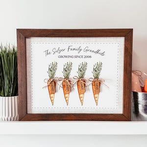 May include: A framed print with four carrot illustrations, each with a name tag and tied with twine. The text reads "The Silzer Family Grandkids GROWING SINCE 2006." The frame is dark brown.
