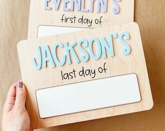 May include: Two wooden signs with blank spaces for writing. The top sign says "EVELYNN'S first day of" and the bottom sign says "JACKSON'S last day of".