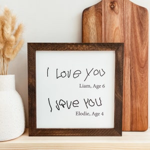 May include: A framed print with two handwritten messages that say "I love you" with the names Liam, Age 6 and Elodie, Age 4 below each message.