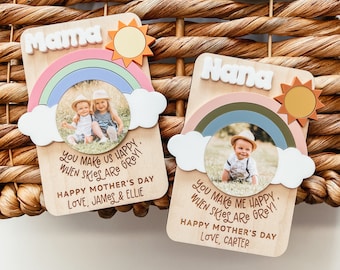 Puede incluir: Dos letreros de madera con diseños de arcoíris y sol. Cada letrero tiene una foto de un niño y un mensaje que dice "You make us happy when skies are grey!" y "Happy Mother's Day". Un letrero dice "Mama" y el otro dice "Nana".