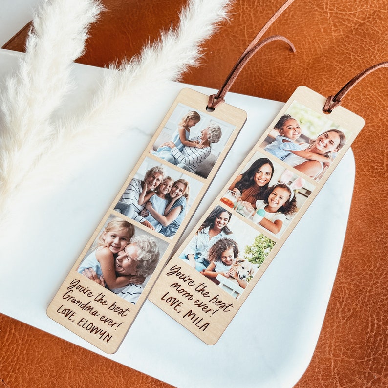 May include: Two wooden bookmarks with photos of families and personalized messages. The bookmark on the left says "You're the best Grandma ever! LOVE, ELOWYN". The bookmark on the right says "You're the best Mom ever! LOVE, MILA".