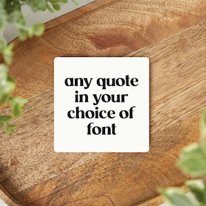 May include: White square coaster with black text that reads "any quote in your choice of font".