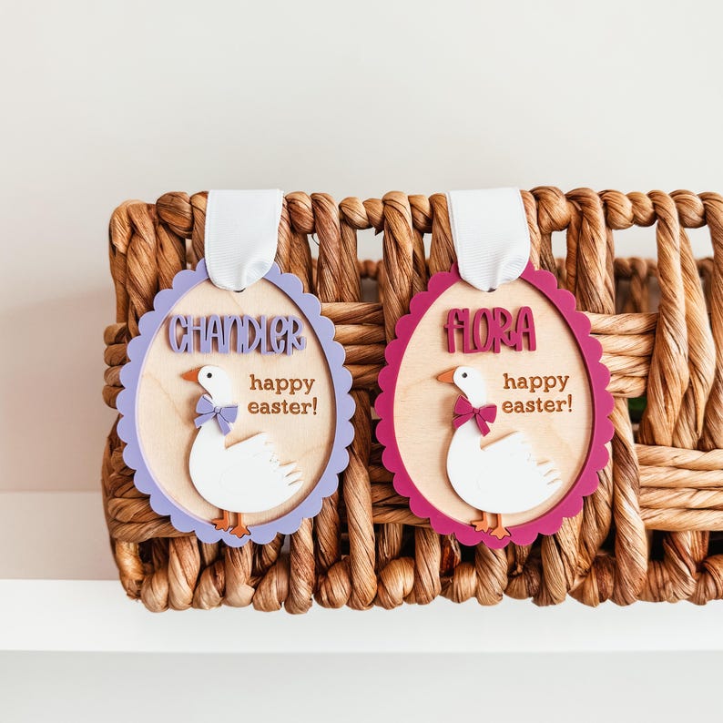 May include: Two purple and red wooden Easter egg ornaments with white duck designs. The ornaments have the names "Chandler" and "Flora" and the text "happy easter!" on them.