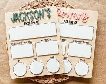 May include: Two wooden first and last day of school boards. One board has the name "Jackson's" in green, the other has "Rowan's" in pink. Each board has spaces for information like age, height, and favorite subject.