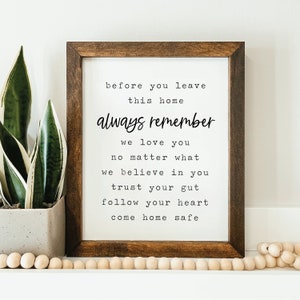 May include: A framed print with a white background and black text that reads "before you leave this home always remember we love you no matter what we believe in you trust your gut follow your heart come home safe".