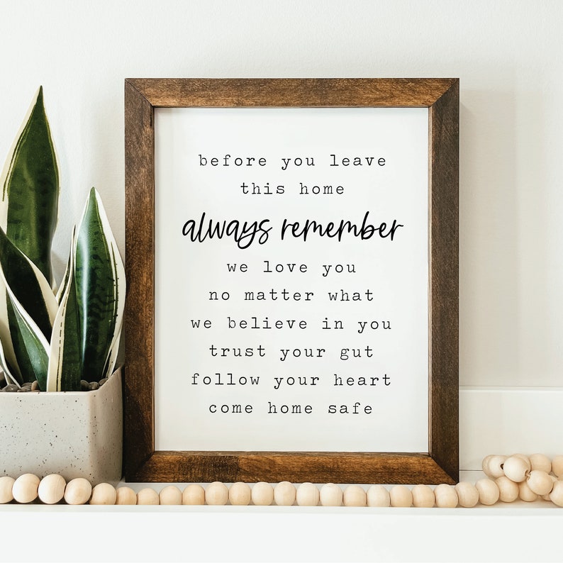 May include: A framed print with a white background and black text that reads "before you leave this home always remember we love you no matter what we believe in you trust your gut follow your heart come home safe".