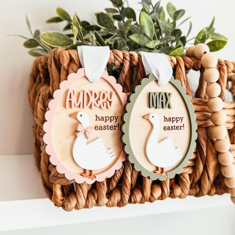 May include: Two wooden Easter ornaments shaped like eggs with a goose design. The pink ornament says "Audrey happy easter!" and the green ornament says "Max happy easter!"