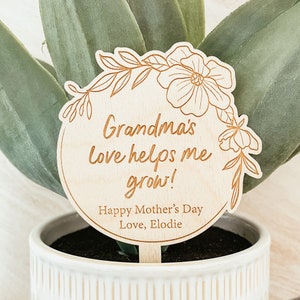 May include: A wooden plant stake with a floral design and the text "Grandma's love helps me grow! Happy Mother's Day Love, Elodie".