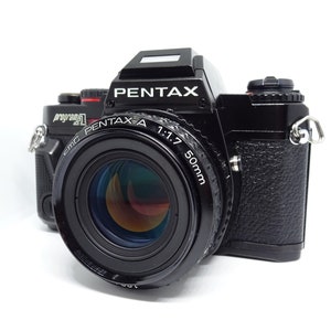 Könnte beinhalten: Schwarze Pentax Program A 35mm Filmkamera mit einem 50mm Objektiv. Auf dem Kameragehäuse steht "PENTAX". Auf dem Objektiv steht "PENTAX-A 1:1.7 50mm". Die Kamera steht vor weißem Hintergrund.