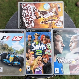 May include: A selection of PSP game cases. Games include "Street", "F1 06", "The Sims 2", and "Pro Evolution Soccer 5". The cases display vibrant graphics and game titles. The games are in clear plastic cases.