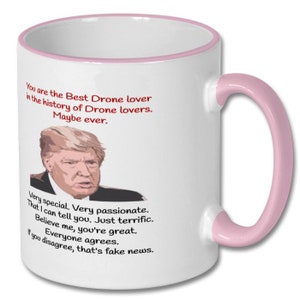 K&ouml;nnte beinhalten: Eine wei&szlig;e Kaffeetasse mit rosafarbenem Rand und Henkel. Die Tasse zeigt ein Cartoon-Bild eines Mannes mit blonden Haaren und einer roten Krawatte. Der Text auf der Tasse lautet: "You are the Best Drone lover in the history of Drone lovers. Maybe ever. Very special. Very passionate. That I can tell you. Just terrific. Believe me, you're great. Everyone agrees. If you disagree, that's fake news."