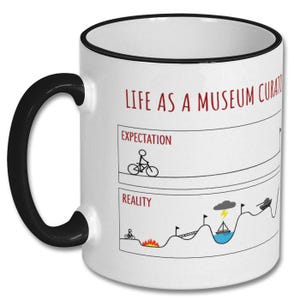 May include: White ceramic mug with a black handle and rim. The mug features the text "LIFE AS A MUSEUM CURATOR" in red, along with a humorous graphic comparing expectations to reality, including a cyclist, fire, and a tank.