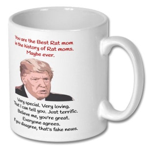 May include: White ceramic coffee mug with a red and black image of a man with the text "You are the Best Rat mom in the history of Rat moms. Maybe ever. Very special. Very loving. That I can tell you. Just terrific. Believe me, you're great. Everyone agrees. If you disagree, that's fake news."