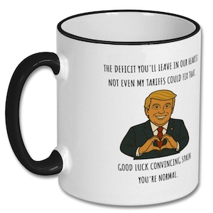May include: White ceramic mug with a black handle and rim. The mug features a cartoon illustration of a man in a suit making a heart shape with his hands, with text that reads "THE DEFICIT YOU'LL LEAVE IN OUR HEARTS!"