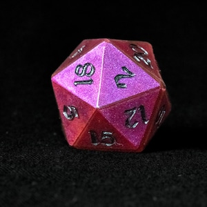 Könnte beinhalten: Ein vielseitiger, polyedrischer Würfel mit Metallic-Finish. Der Würfel ist eine Kombination aus Rosa- und Rottönen mit schwarzen Ziffern. Der Würfel wird für Tabletop-Rollenspiele verwendet.