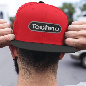 May include: A red and black baseball cap with a black oval patch that says "Techno" in white letters.