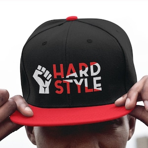 May include: A black and red baseball cap with a white fist and the text "HARD STYLE" on the front.