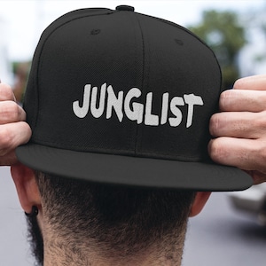 May include: A black baseball cap with a white embroidered logo that says "JUNGLIST".
