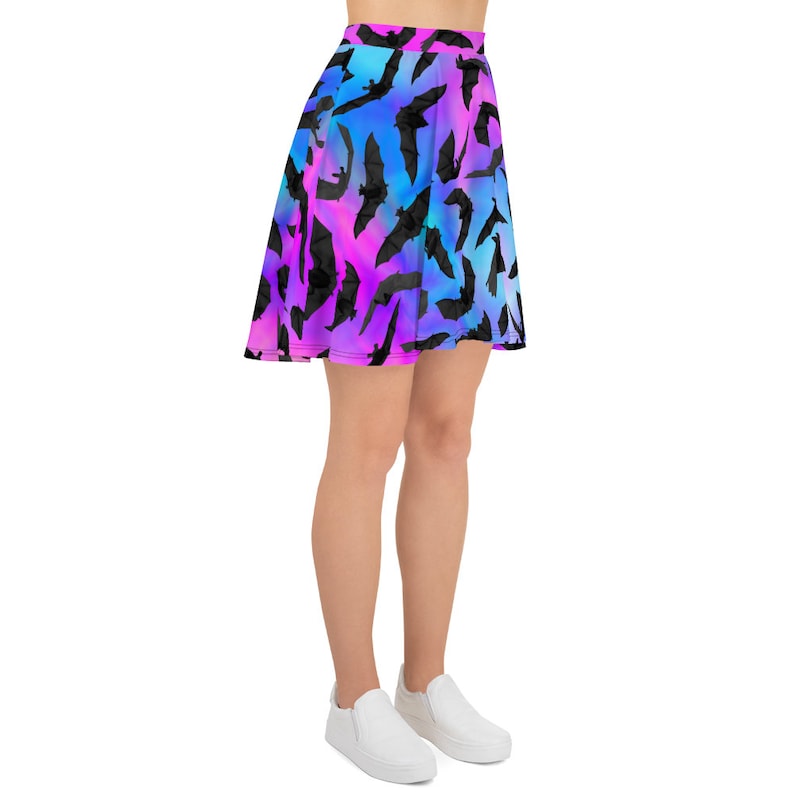 May include: A skater skirt with a gradient pattern of pink, blue, and purple. The skirt is covered in a repeating pattern of black bats.