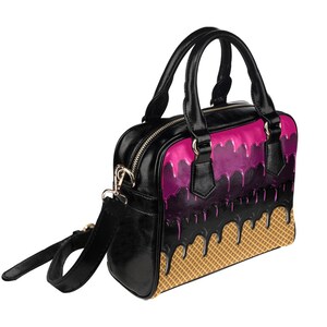 Puede incluir: Bolso negro con un dise&ntilde;o de cono de helado rosa y negro. El bolso tiene un asa superior y una correa para el hombro.