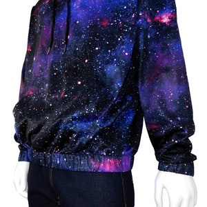 May include: A black hoodie with a galaxy print featuring shades of blue, purple, and pink. The hoodie has a drawstring hood and a ribbed waistband.
