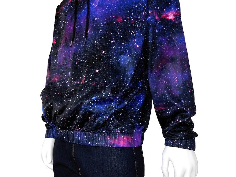 May include: A black hoodie with a galaxy print featuring shades of blue, purple, and pink. The hoodie has a drawstring hood and a ribbed waistband.