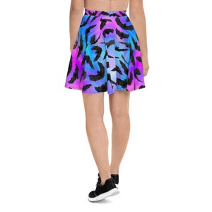 May include: A short, flowy skirt with a colorful ombre pattern of pink, blue, and purple. The skirt is covered in a repeating pattern of black bats.