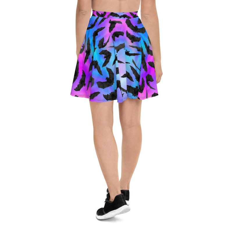 May include: A short, flowy skirt with a colorful ombre pattern of pink, blue, and purple. The skirt is covered in a repeating pattern of black bats.