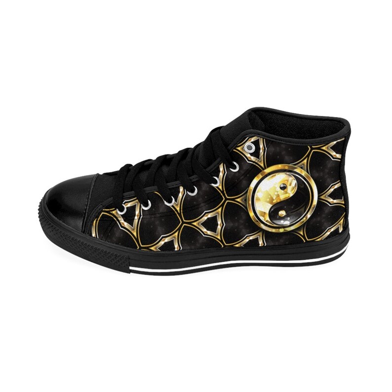 May include: Black high-top canvas sneakers with a gold and black geometric pattern. The design includes a gold and white Yin and Yang symbol on the side. The sneakers have black laces and a black rubber sole.