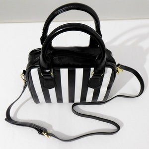 May include: A black and white striped handbag with a black leather top and a gold chain strap.
