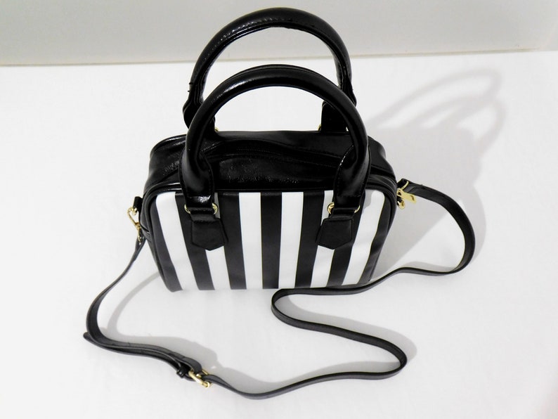 May include: A black and white striped handbag with a black leather top and a gold chain strap.