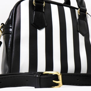 May include: A black and white striped handbag with a black leather strap and gold hardware.