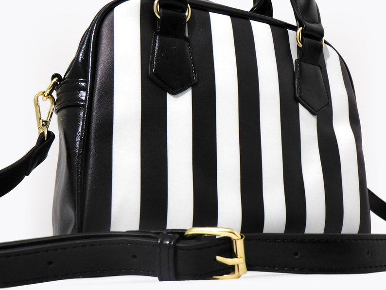 May include: A black and white striped handbag with a black leather strap and gold hardware.