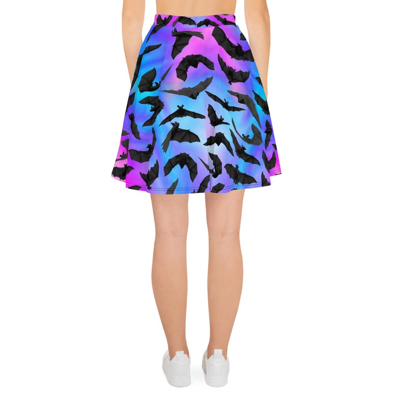 May include: A black skater skirt with a colorful gradient pattern of pink, blue, and purple. The skirt is covered in a repeating pattern of black bat silhouettes.