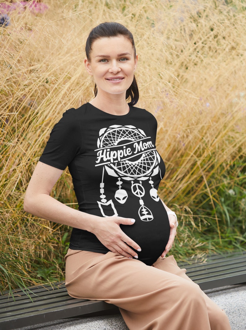 Może przedstawiać: Czarny T-shirt z białym wzorem łapacza sn&oacute;w i napisem "Hippie Mom". Łapacz sn&oacute;w ma znak pokoju, stylizowanego kosmitę i drzewo życia zwisające z niego.
