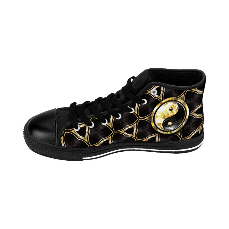 May include: Black high-top sneaker featuring a gold and black geometric pattern with a gold-framed yin-yang symbol on the side. The shoe has black laces, a black toe cap, and a white stripe along the sole.