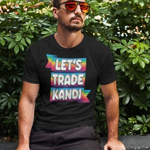 May include: A black t-shirt with the text "Let's Trade KANDI" in rainbow letters on a banner.