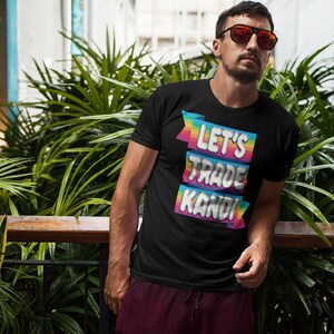 May include: A black t-shirt with a rainbow-colored graphic that says "Let's Trade Kandi".